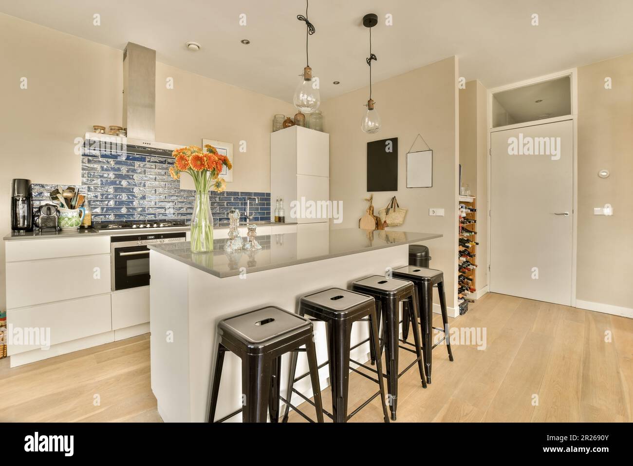una cucina con armadi bianchi e sgabelli neri al centro della stanza, c'è  un vaso di fiori sull'isola Foto stock - Alamy