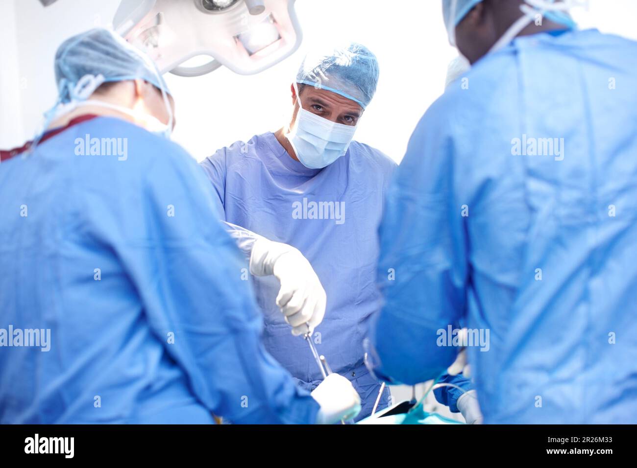Passando sotto il coltello. Ritratto di un chirurgo maschio che esegue un intervento chirurgico su un paziente in una sala operatoria. Foto Stock
