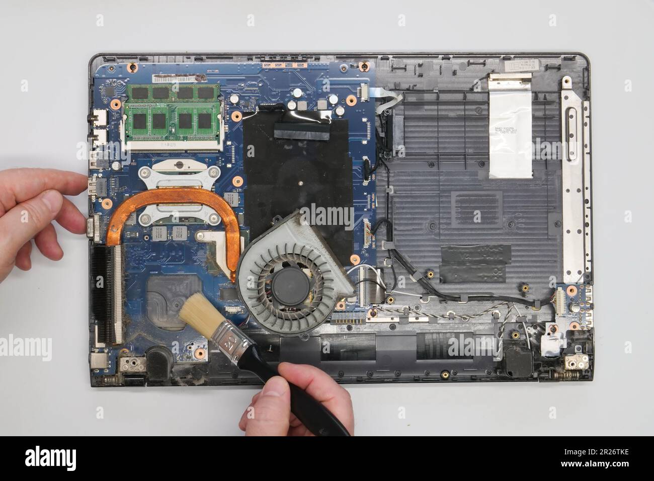 Riparazione pulizia di un computer portatile smontato su sfondo bianco. Isolato. Computer polveroso riparato in un'officina di assistenza. Scheda madre per computer, chip Foto Stock
