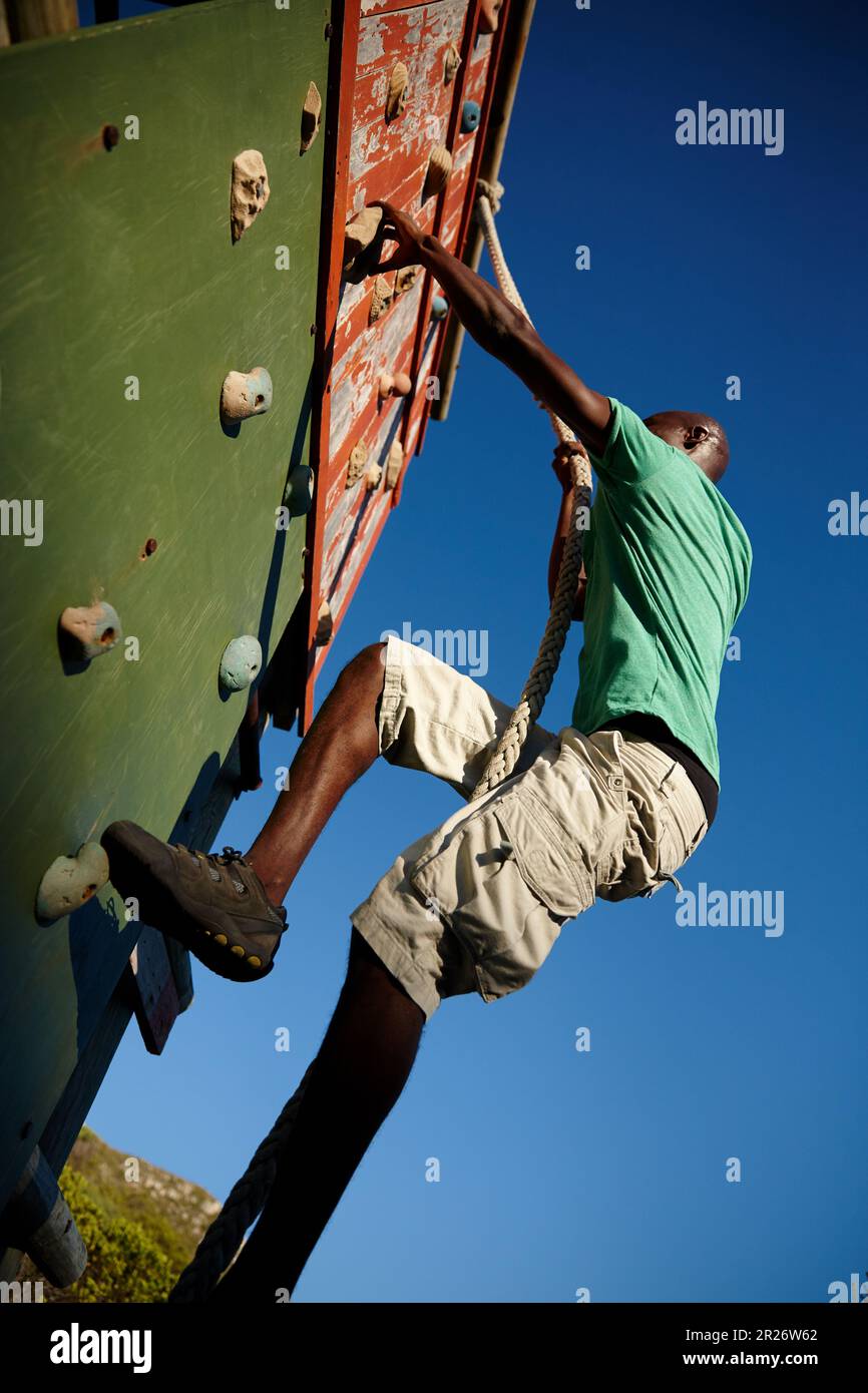 Energia e persistenza conquistano tutte le cose. un giovane che si arrampica su un ostacolo al bootcamp militare. Foto Stock
