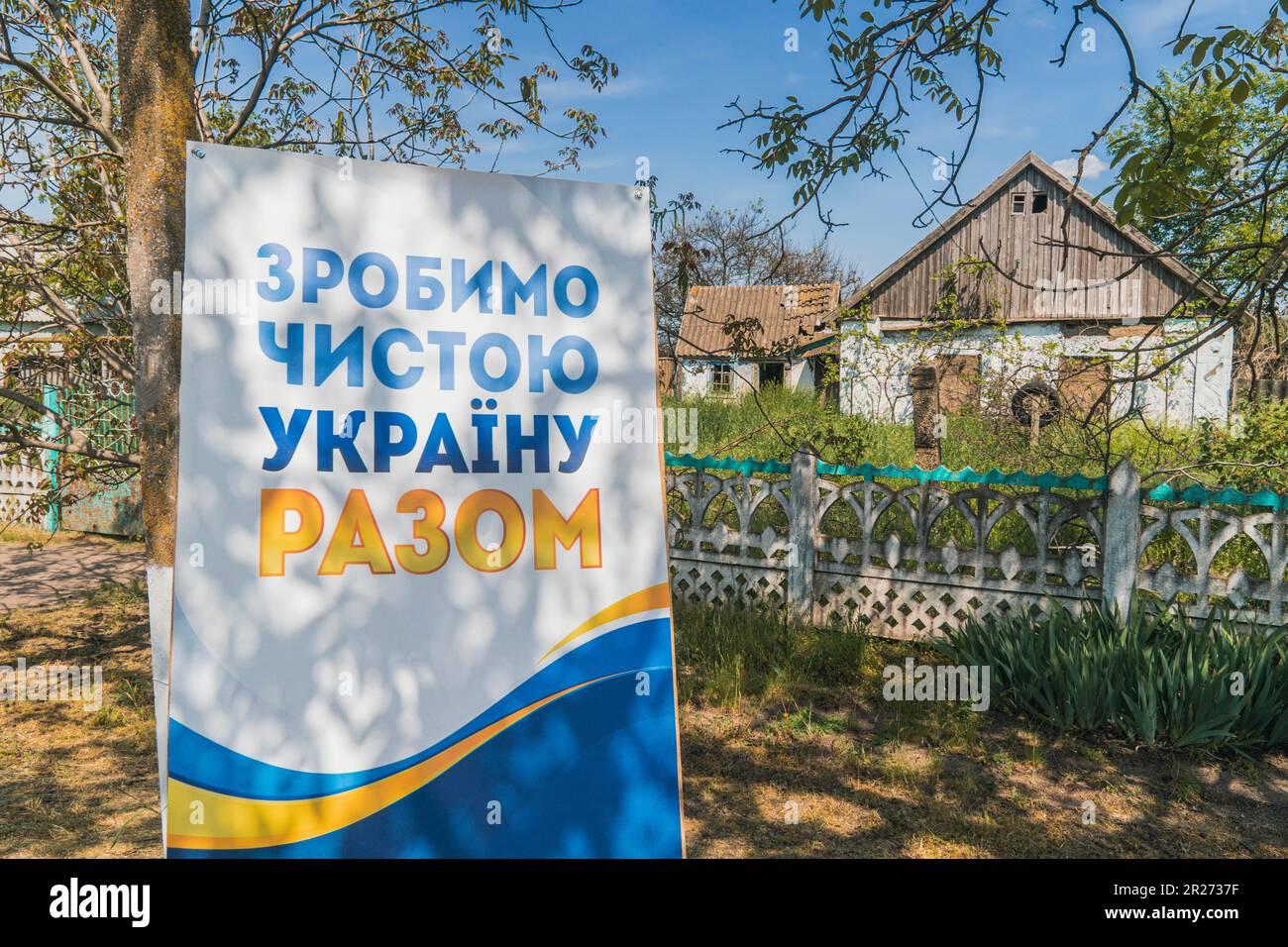 Poster di fronte a casa, danneggiato da conchiglie. Traduzione dell'iscrizione sul poster - facciamo l'Ucraina pulita insieme. Ripresa dopo la guerra Foto Stock