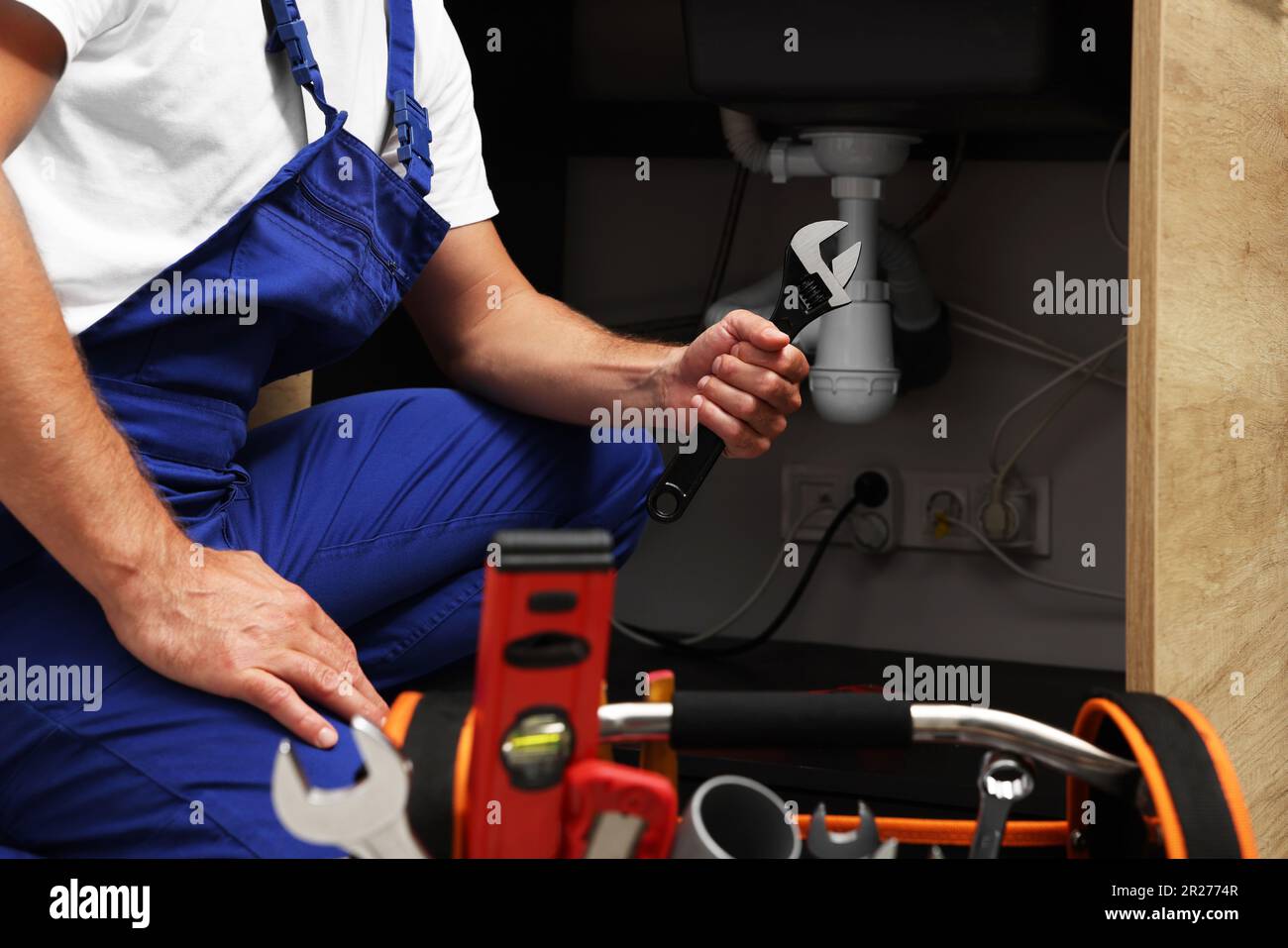 Idraulico professionale con chiave regolabile sotto lavello da cucina,  primo piano Foto stock - Alamy