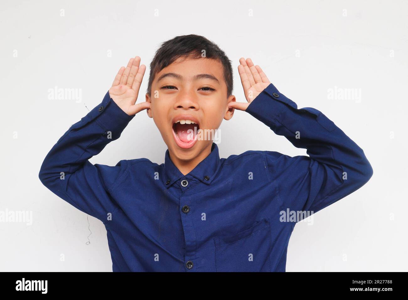 Ragazzo allegro in faccia divertente espresso, isolato su sfondo bianco. Un ragazzo di 10 anni che fa un volto divertente. Foto Stock