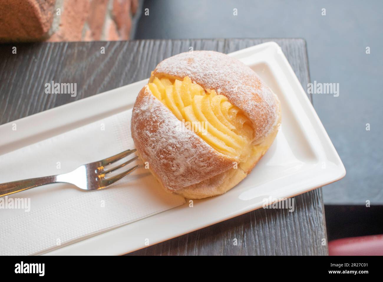 Ciambella portoghese o Berliner con crema di uova su un piatto bianco. Consiste in un impasto dolce fritto ripieno di panna e zucchero. Selettivo fo Foto Stock