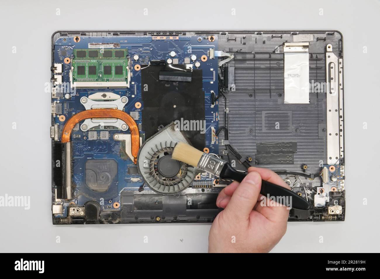 Riparazione pulizia di un computer portatile smontato su sfondo bianco. Isolato. Computer polveroso riparato in un'officina di assistenza. Scheda madre per computer, chip Foto Stock