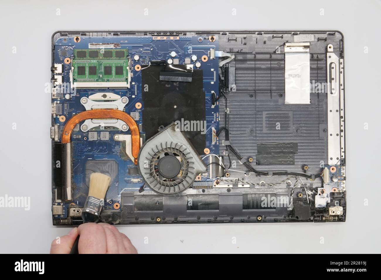 Riparazione pulizia di un computer portatile smontato su sfondo bianco. Isolato. Computer polveroso riparato in un'officina di assistenza. Scheda madre per computer, chip Foto Stock