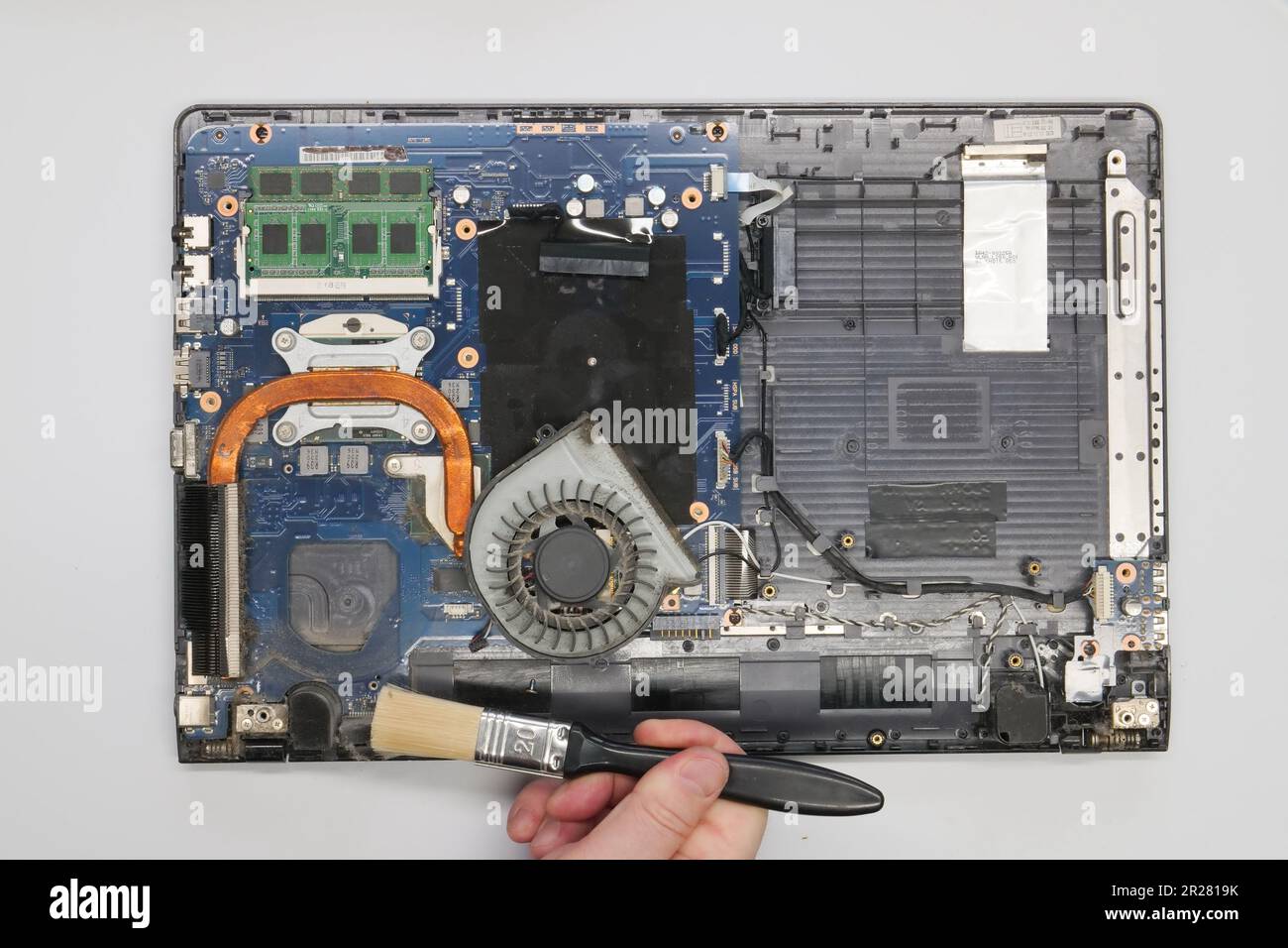 Riparazione pulizia di un computer portatile smontato su sfondo bianco. Isolato. Computer polveroso riparato in un'officina di assistenza. Scheda madre per computer, chip Foto Stock