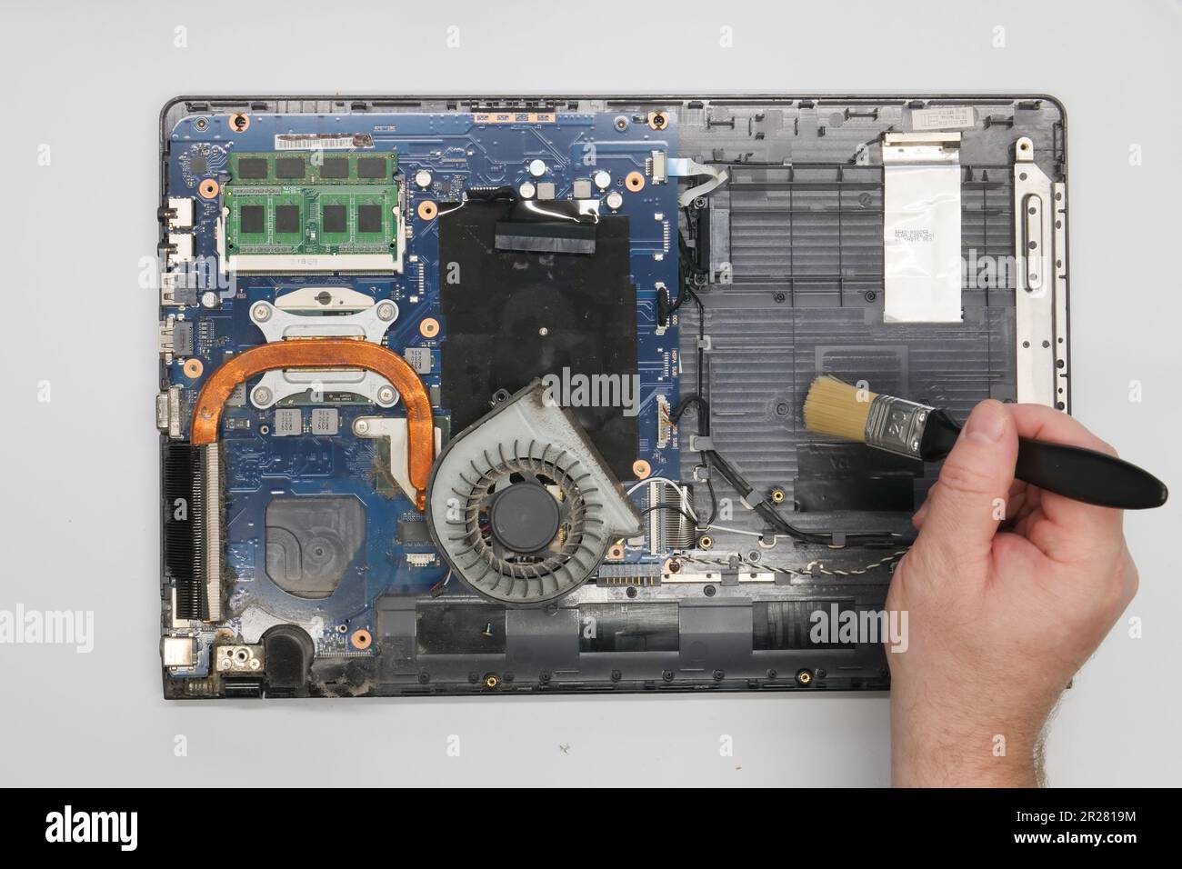 Riparazione pulizia di un computer portatile smontato su sfondo bianco. Isolato. Computer polveroso riparato in un'officina di assistenza. Scheda madre per computer, chip Foto Stock
