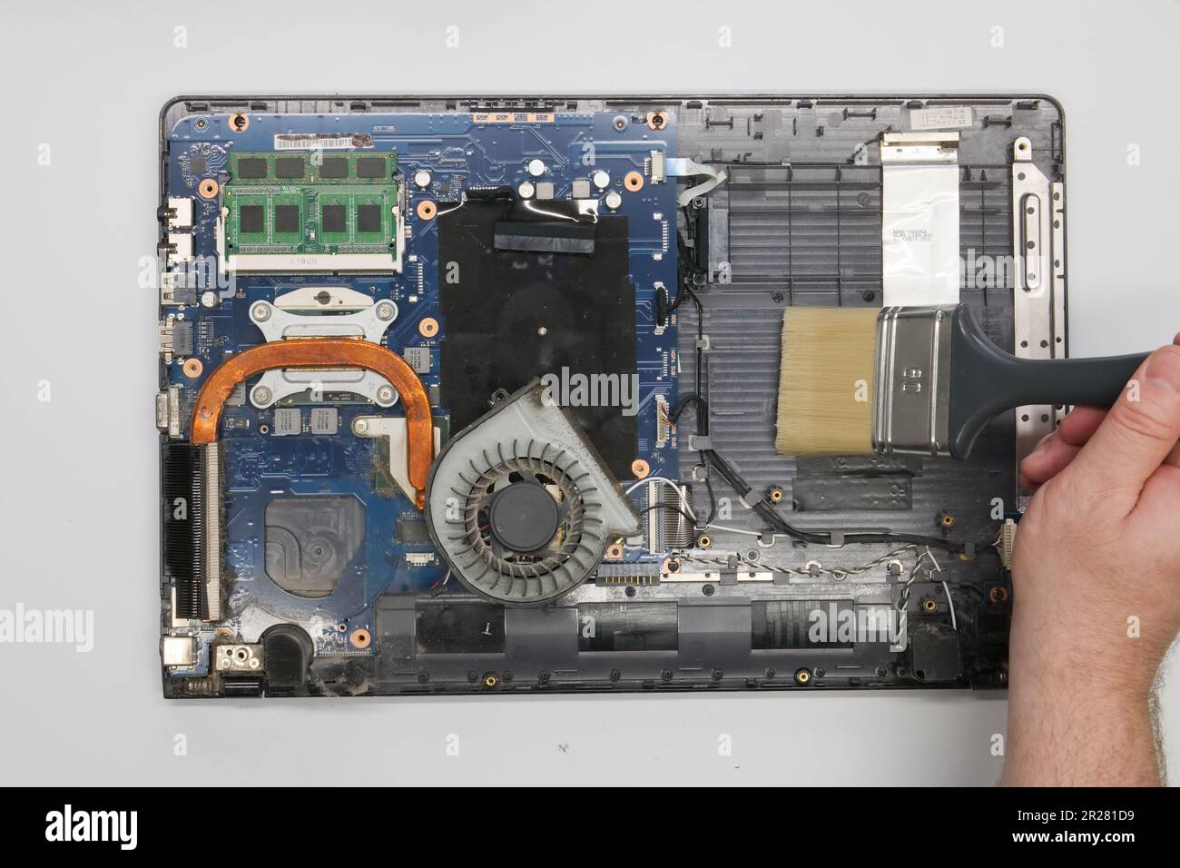 Riparazione pulizia di un computer portatile smontato su sfondo bianco. Isolato. Computer polveroso riparato in un'officina di assistenza. Scheda madre per computer, chip Foto Stock