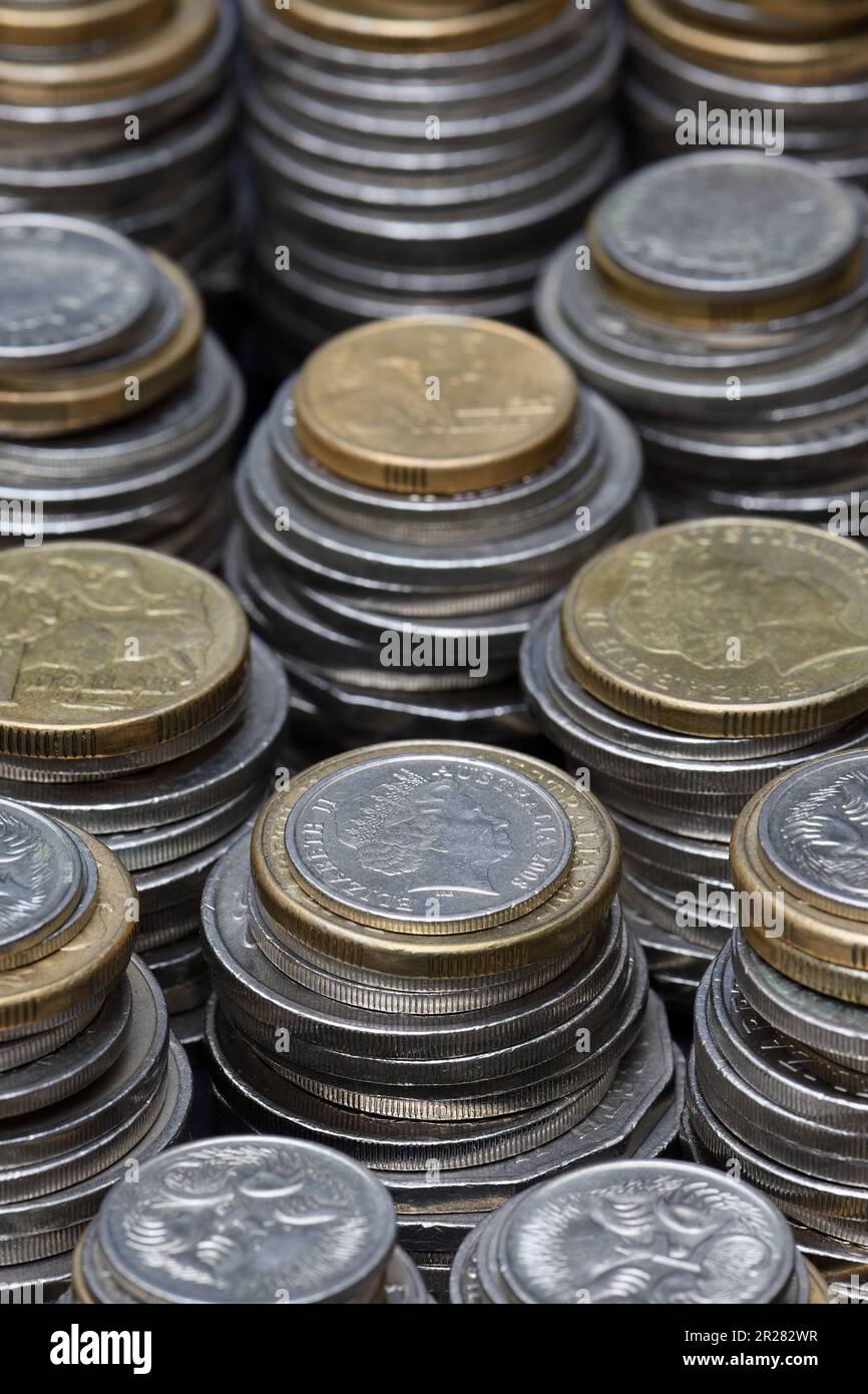 Un mucchio di monete da due e un dollaro australiani, cinquanta, venti, dieci e cinque centesimi che riempiono la cornice con un fuoco poco profondo in illuminazione soffusa Foto Stock