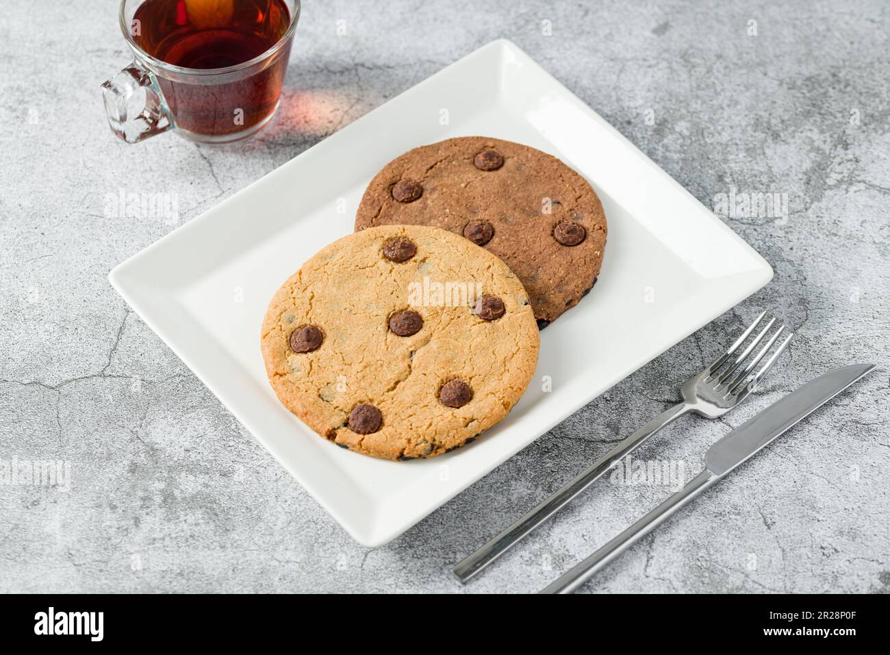Biscotti con scaglie di cioccolato e tè sul tavolo di pietra Foto Stock