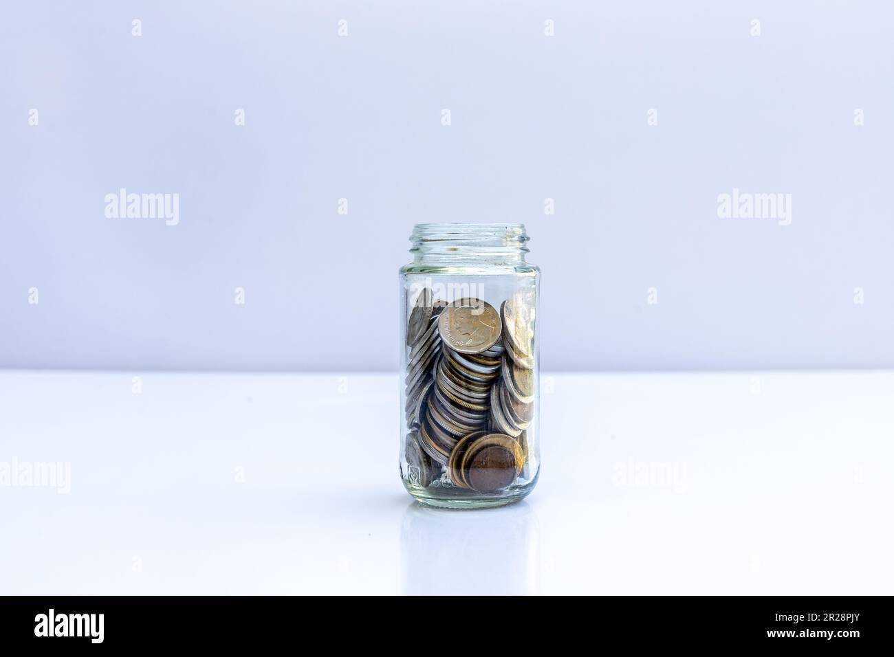Vasetto pieno di monete su sfondo bianco. Business finanziario e risparmio di denaro concetto. Foto Stock