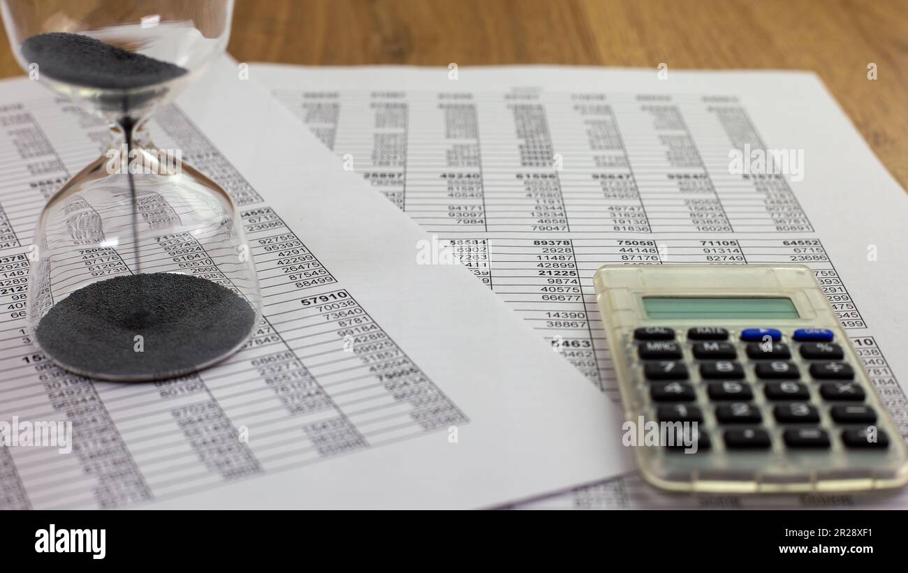 concetto di banner o scadenza dei pagamenti, clessidra e calcolatrice su fogli di calcolo, focalizzazione selettiva Foto Stock