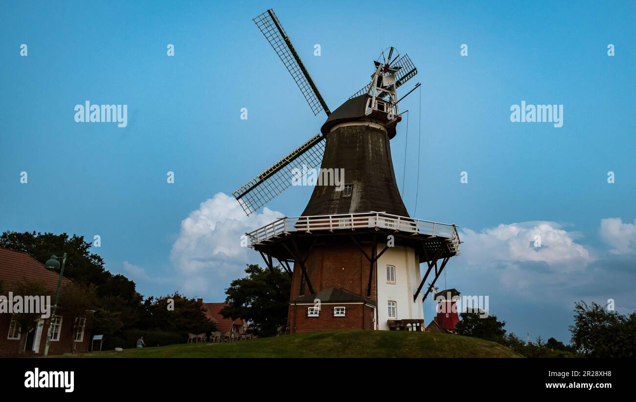 Cattura del vecchio mulino a vento vicino a Greetsiel nella Frisia Orientale sotto un cielo blu Foto Stock