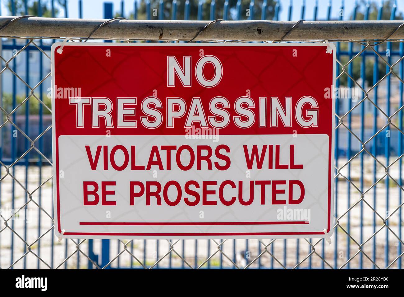 Cartello "No Trespassing - i violatori saranno perseguiti" sulla recinzione metallica. Cantiere e soleggiato Foto Stock