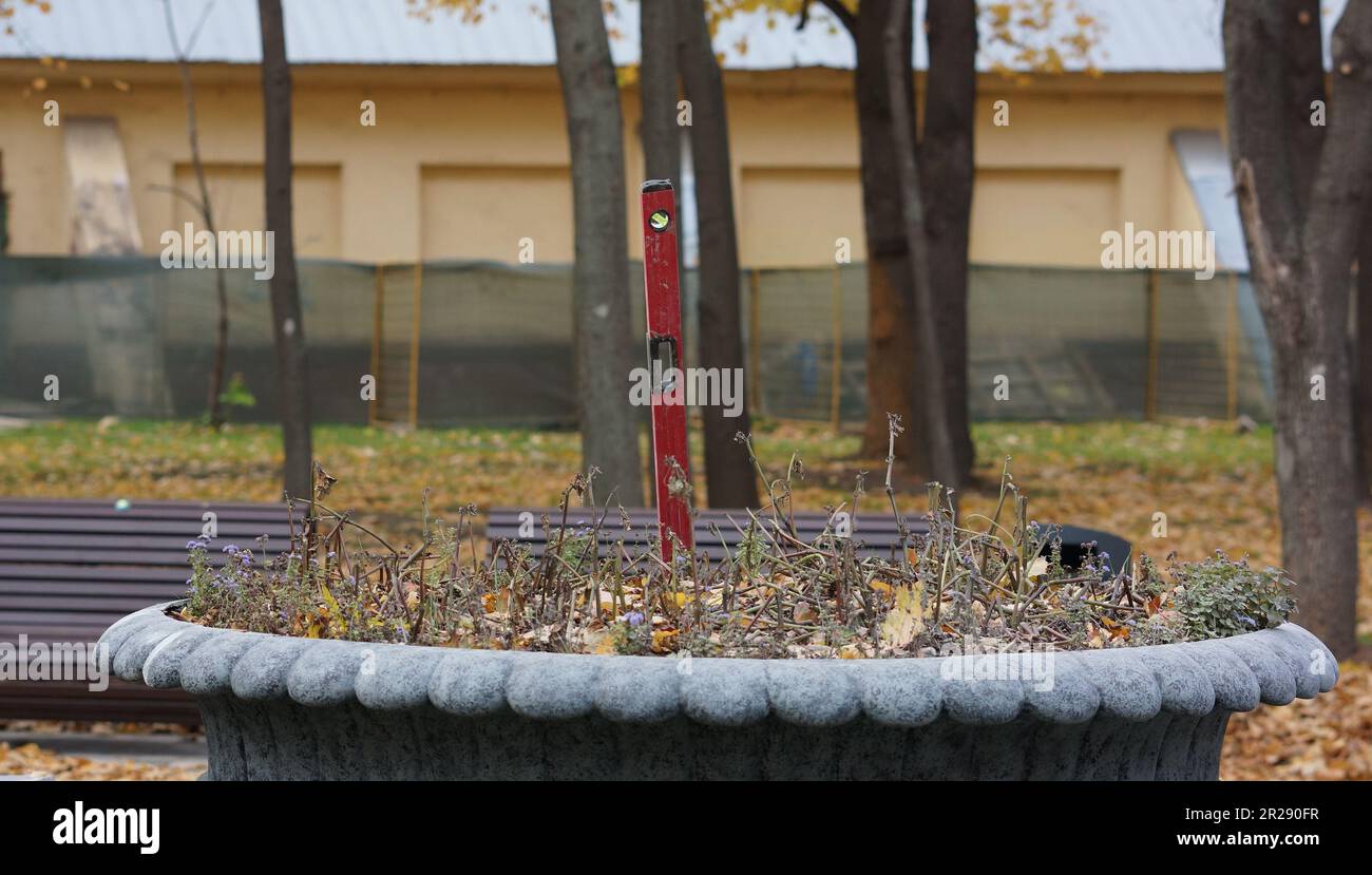 Mosca, autunno. Park, qualcuno ha lasciato la sua livella di spirito in un letto di fiori. Situazione tipica del parco a Mosca. Parco a Moskau, Wasserwaage im Blumenbeet Foto Stock