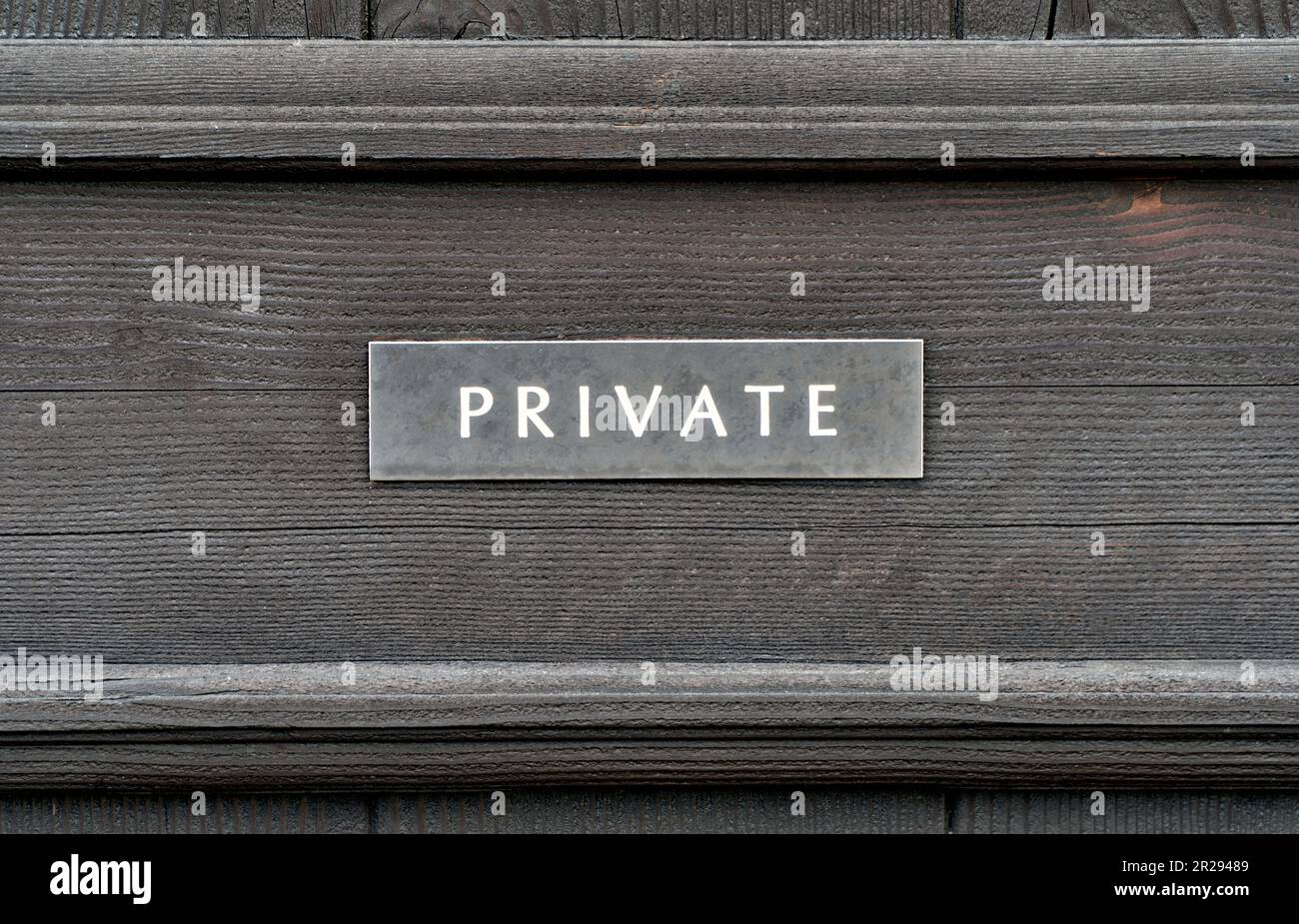Un cartello 'privato' stagionato su una porta di legno Foto Stock