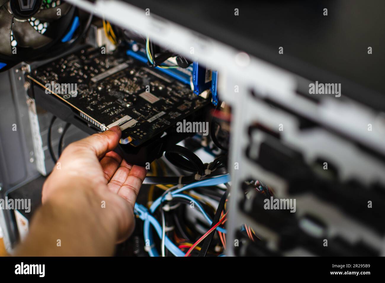 La mano di un tecnico tiene la scheda grafica per ripararla. La scheda VGA è danneggiata e il computer non funziona. La scheda video non visualizza un PC sc Foto Stock