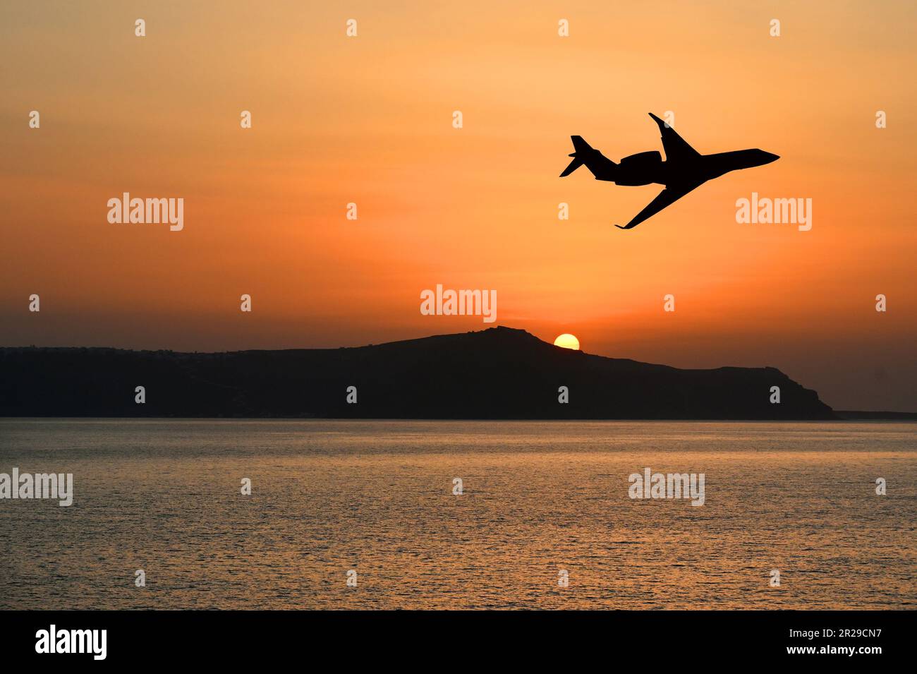 Silhouette di un jet privato executive che sorvola un'isola al tramonto. Concetto di viaggio di lusso. Spazio di copia. Nessuna gente. Foto Stock