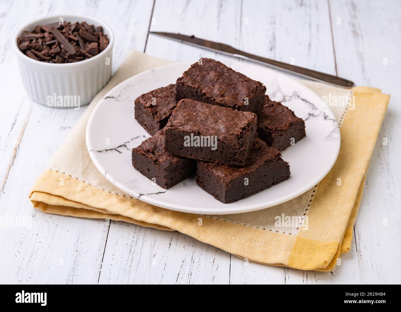 Brownie su un piatto con pezzi di cioccolato su un tavolo di legno bianco. Foto Stock