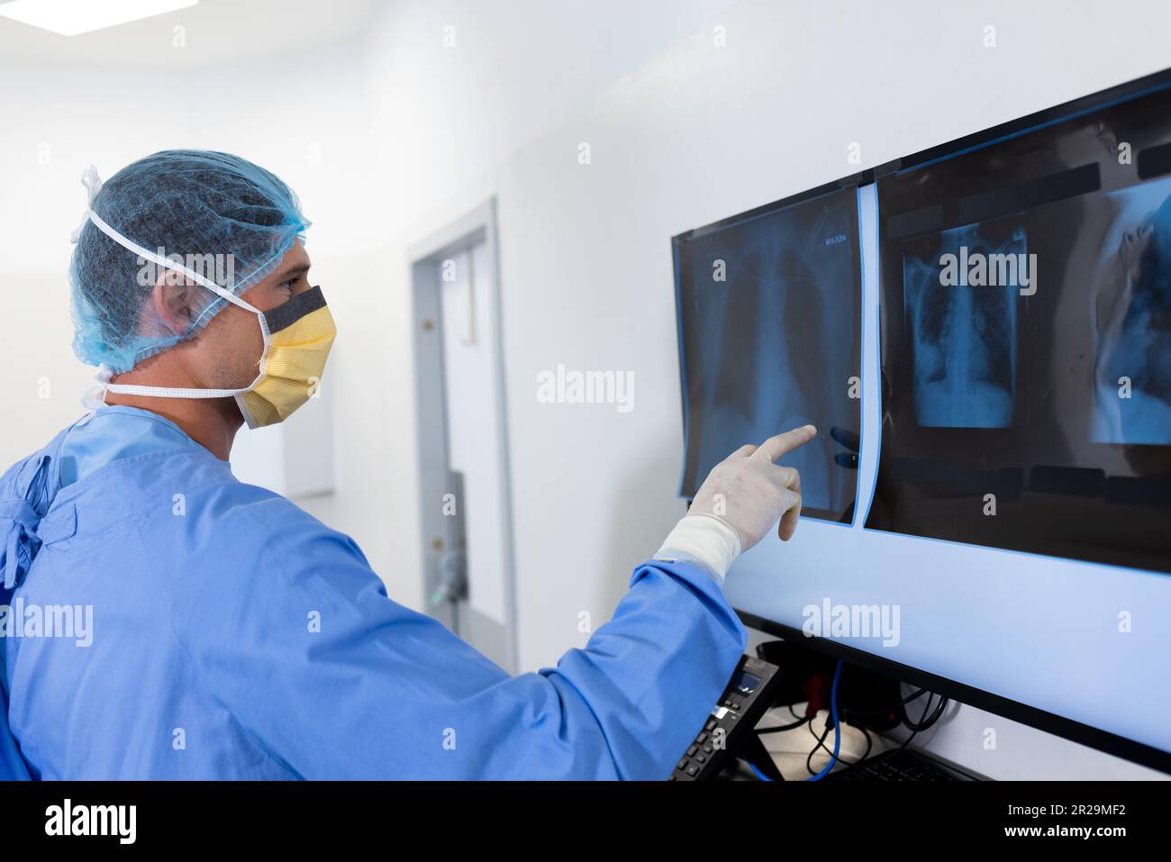 Chirurgo caucasico maschio che studia i raggi x sullo schermo in sala operatoria Foto Stock