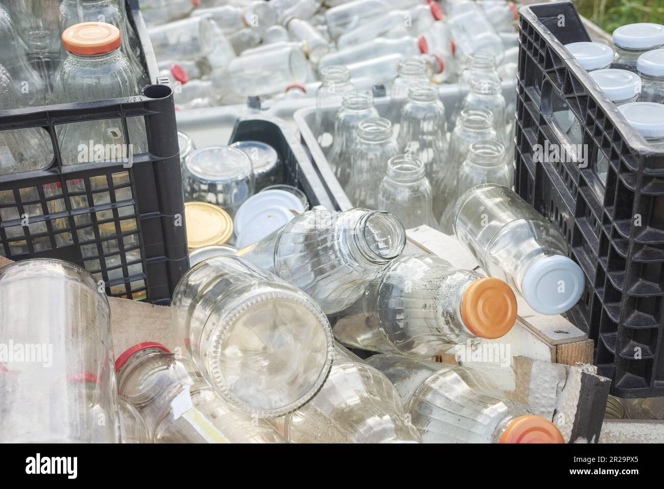Vari tipi di bottiglie di vetro vuote immagazzinate in contenitori per il riciclaggio, focus selettivo. Foto Stock