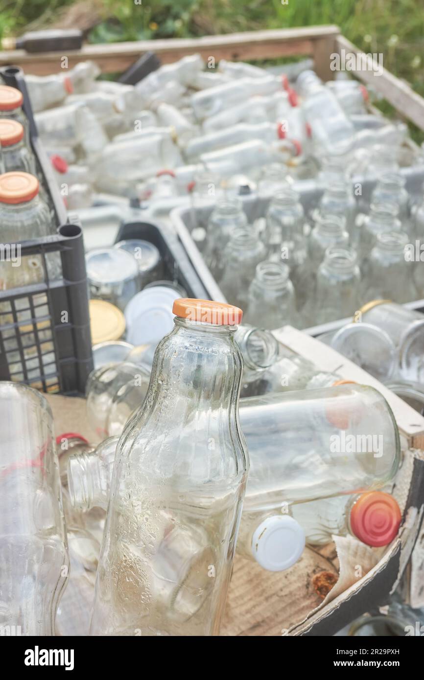 Vari tipi di bottiglie di vetro vuote immagazzinate in contenitori per il riciclaggio, focus selettivo. Foto Stock