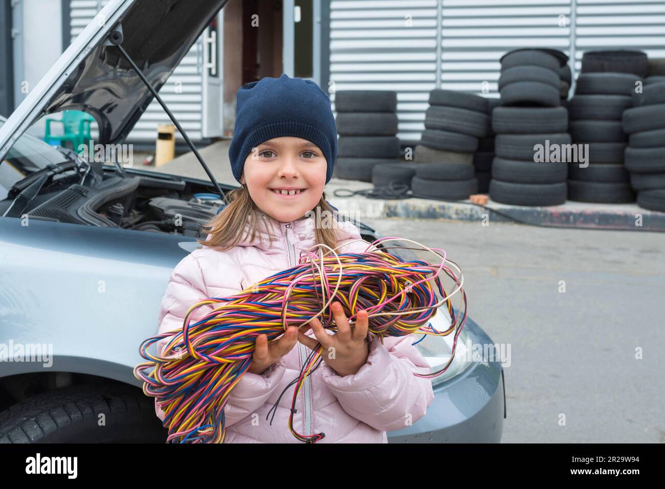 La bambina con un filo nelle sue mani lavora in un servizio auto. Servizio di riparazione Foto Stock