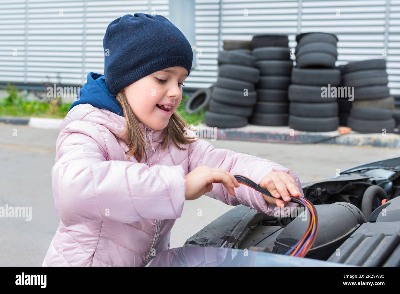 Un bambino sta riparando un'automobile all'aperto. Servizio di riparazione. Servizio auto, concetto di riparazione auto Foto Stock