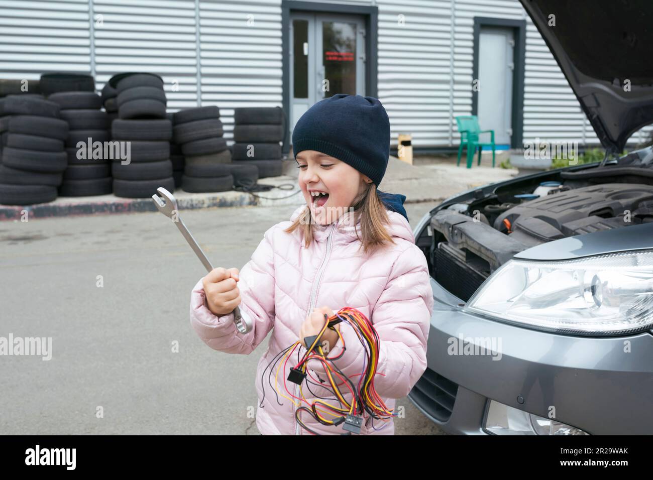 Un bambino meccanico lavora in un garage, all'aperto. Servizi di riparazione auto. Servizio auto. Foto Stock