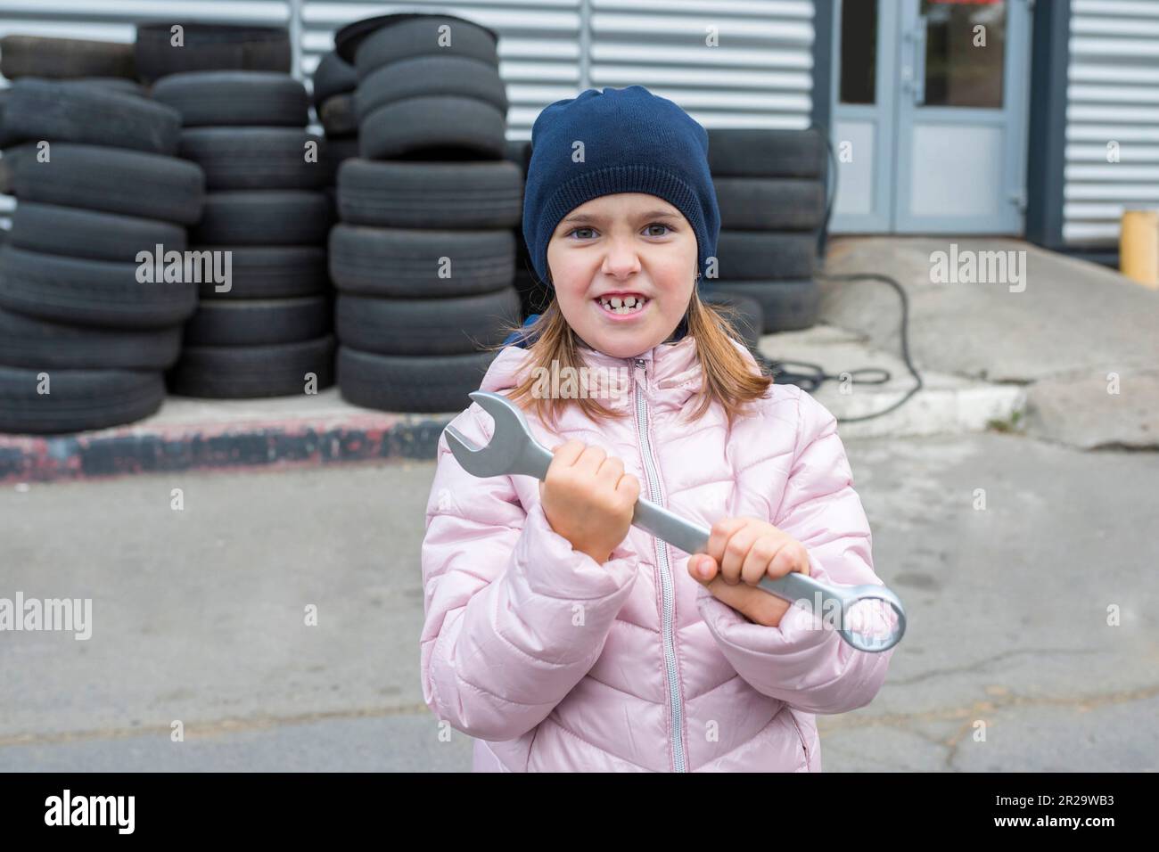 Meccanico per bambini, con una chiave in mano sullo sfondo del garage. Servizio di riparazione Foto Stock
