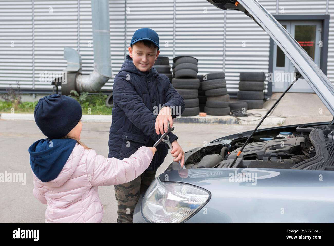 I bambini riparano l'auto all'aperto. Concetto di riparazione automatica, stile di vita Foto Stock