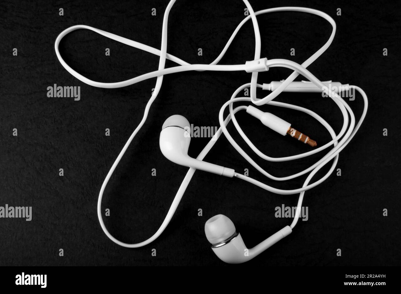 La cuffia musicale si trova su uno sfondo nero. accessorio mobile. Cuffie cablate. Foto Stock