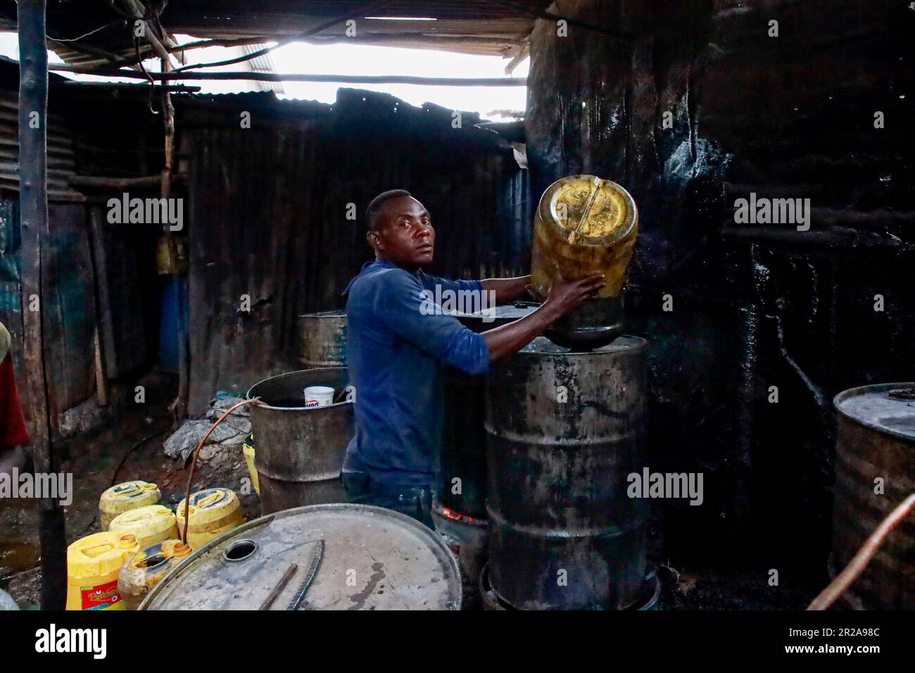 Un lavoratore si pone in un negozio di birra a Kibera Slum. I residenti di Nairobi camminano per le strade alla ricerca di pascoli più verdi nel mezzo dell'alto costo della vita e delle turbolenze economiche. Foto Stock