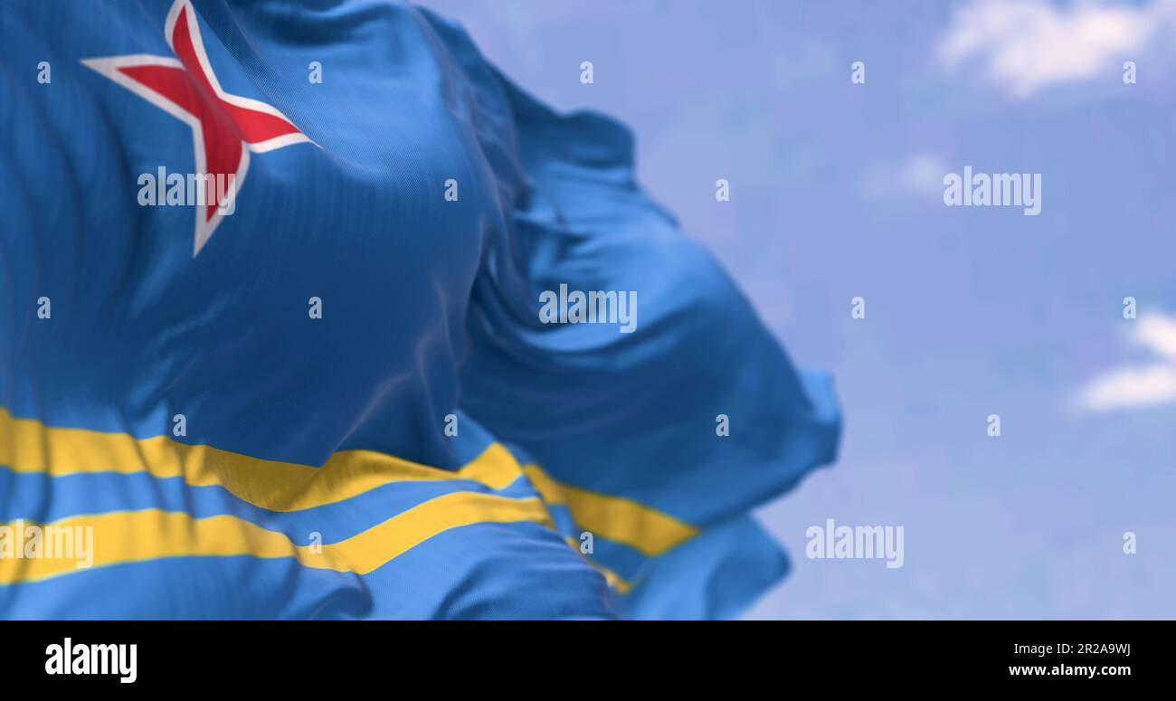 Bandiera di Aruba che sventola nel vento in una giornata limpida. Campo azzurro, 2 strisce gialle, stella rossa a 4 punte. I colori rappresentano il mare, l'abbondanza, la pace ed o Foto Stock