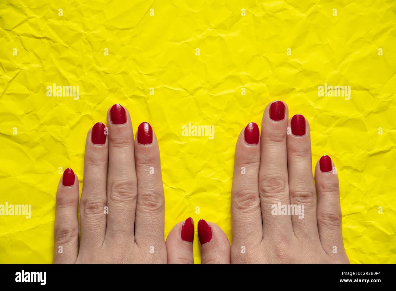 mano femminile su sfondo giallo sbriciolato primo piano Foto Stock