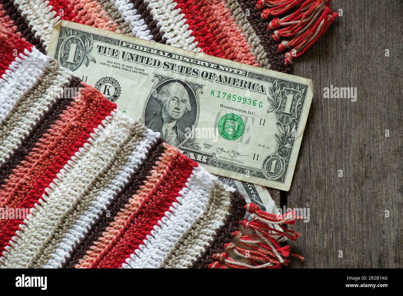 Su uno sfondo di legno con un tovagliolo multicolore a strisce si trova un dollaro americano Foto Stock