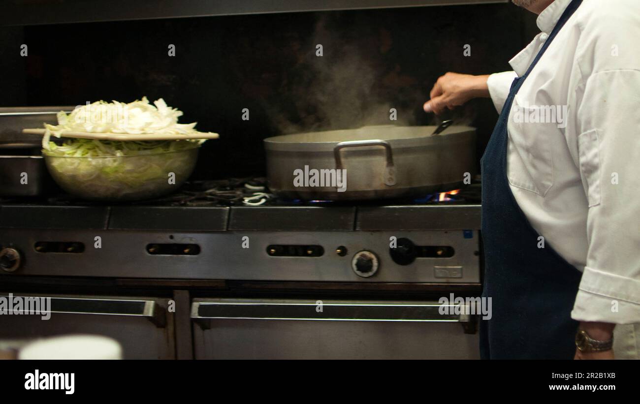 Uomo irriconoscibile che cucina in una cucina professionale. Pentola di cottura Foto Stock