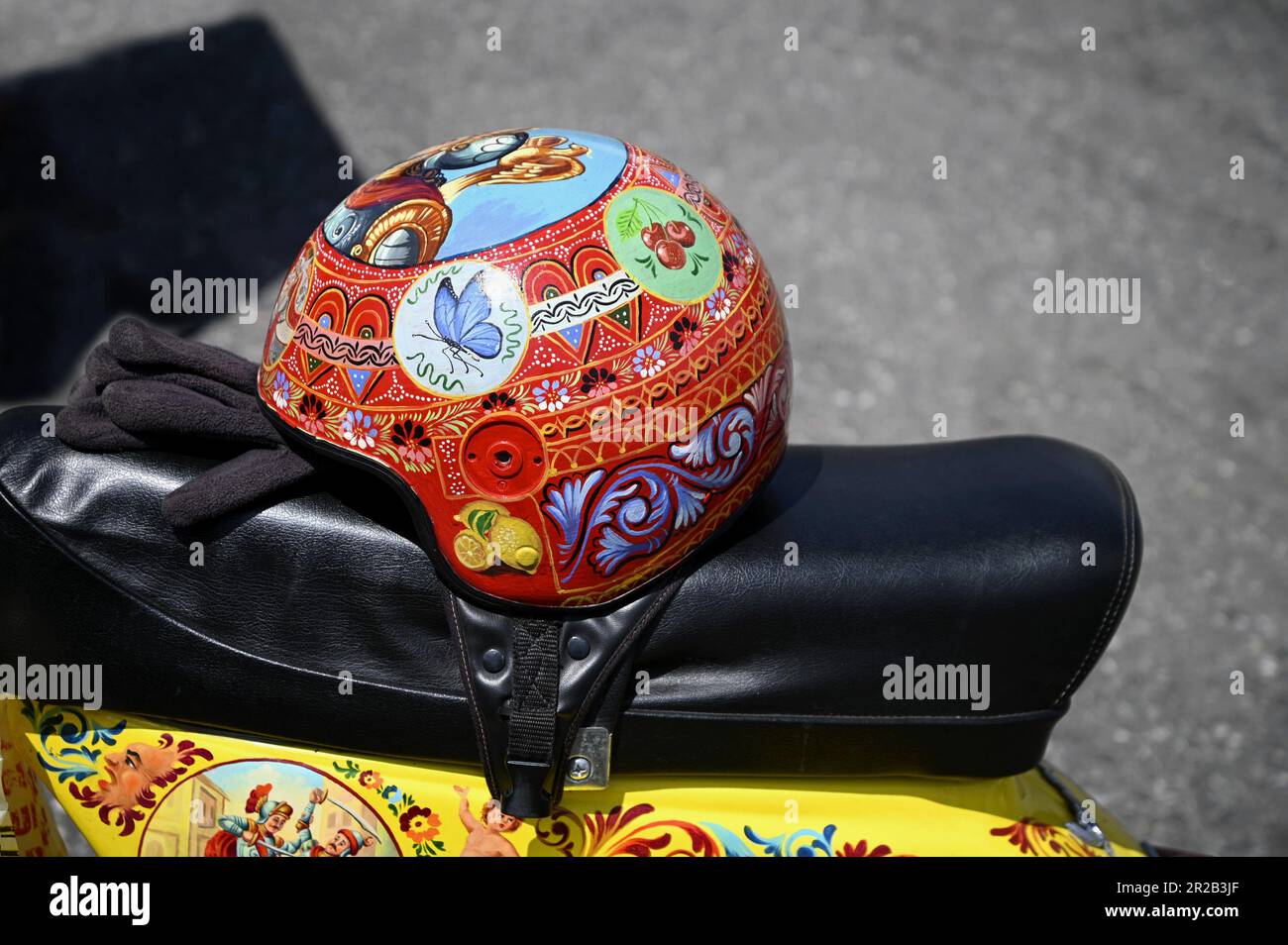 Vespa d'epoca su misura con casco dipinto a mano e decorata con iconografia popolare siciliana in Sicilia, Italia. Foto Stock