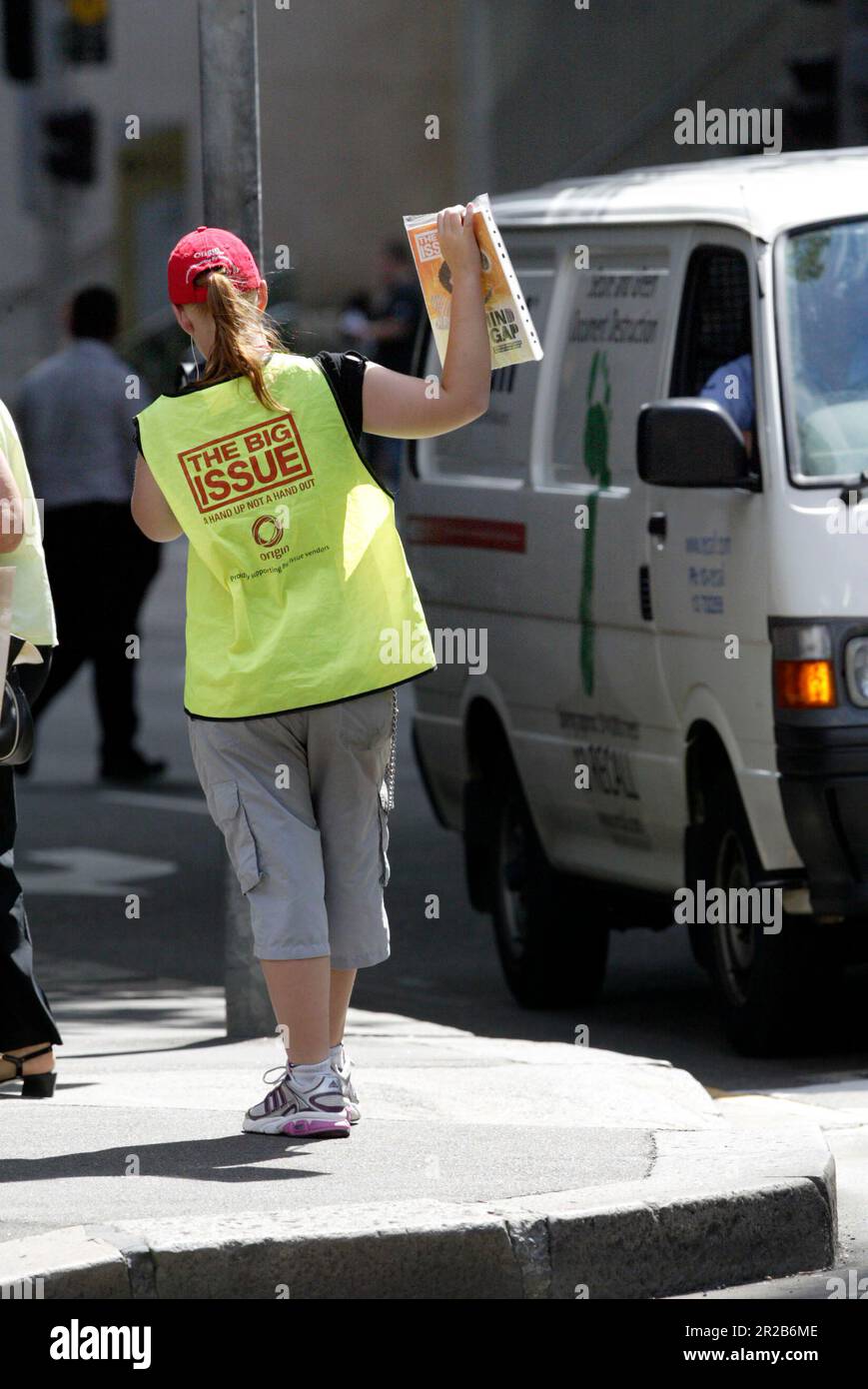 Un venditore di strada che vende The Big Issue, una rivista quindicinale che presenta gli affari attuali, l'intrattenimento, la fotografia e il commento, venduto per le strade di città e città in tutta l'Australia da persone che vivono senza casa o disoccupazione di lunga durata. Aiuta le persone ad aiutare se stesse, poiché i fornitori mantengono la metà del prezzo di copertura di $5 dollari di ogni rivista che vendono. Posizione: All'angolo tra Elizabeth e King Street, Sydney. Foto Stock