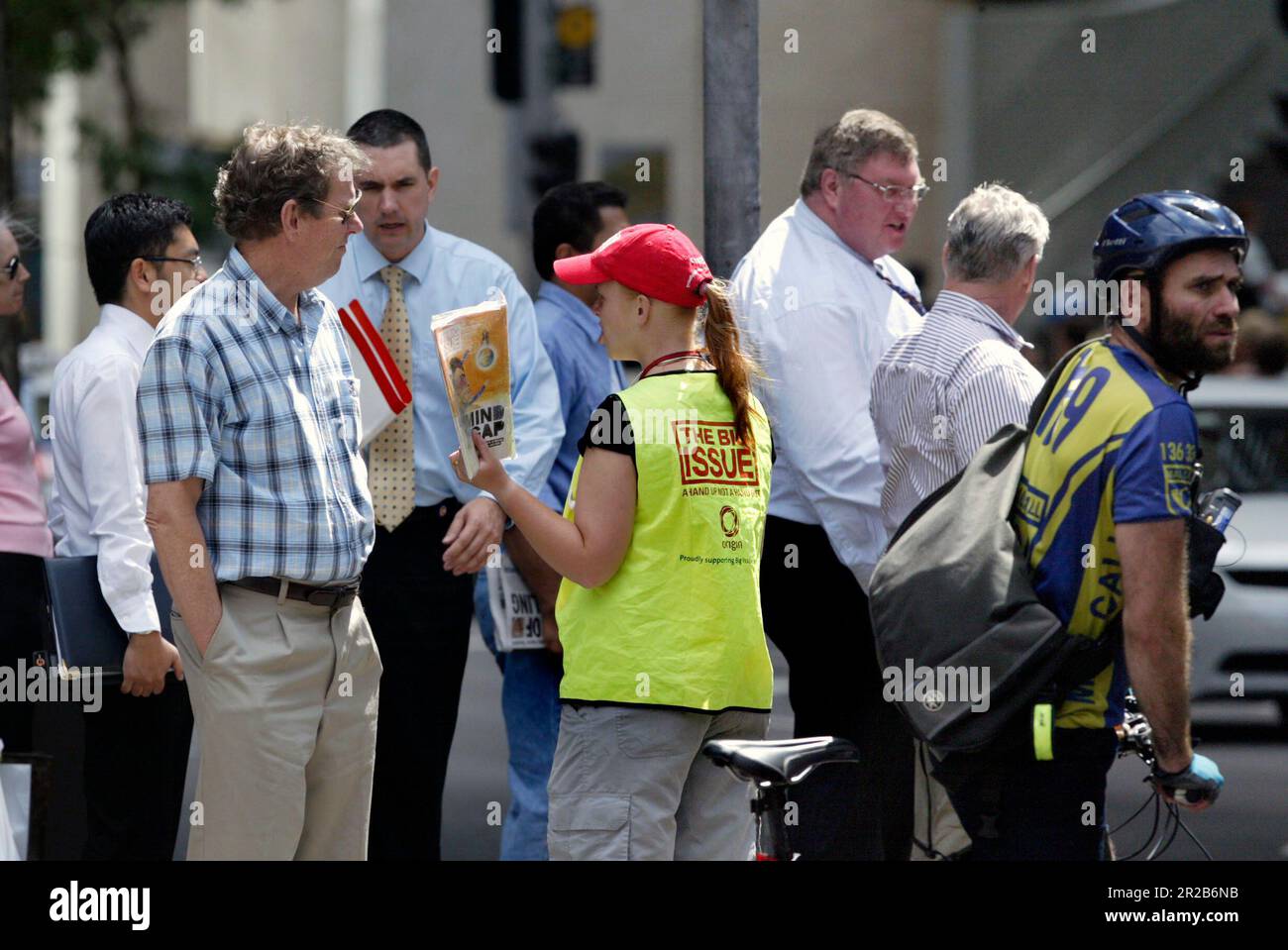 Un venditore di strada che vende The Big Issue, una rivista quindicinale che presenta gli affari attuali, l'intrattenimento, la fotografia e il commento, venduto per le strade di città e città in tutta l'Australia da persone che vivono senza casa o disoccupazione di lunga durata. Aiuta le persone ad aiutare se stesse, poiché i fornitori mantengono la metà del prezzo di copertura di $5 dollari di ogni rivista che vendono. Posizione: All'angolo tra Elizabeth e King Street, Sydney. Foto Stock