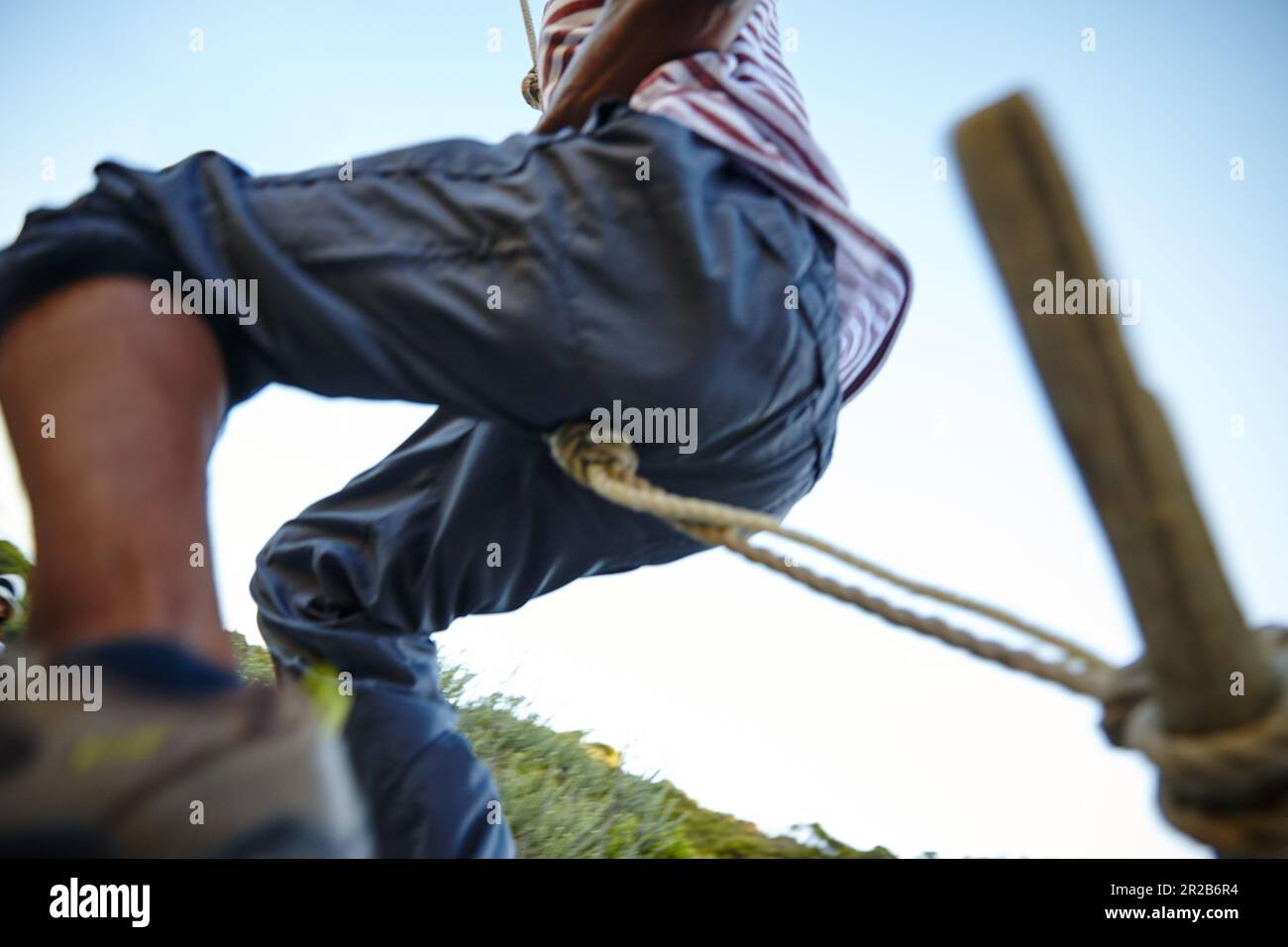 Ora per una corsa di adrenalina... un uomo che oscilla su una corda al bootcamp. Foto Stock
