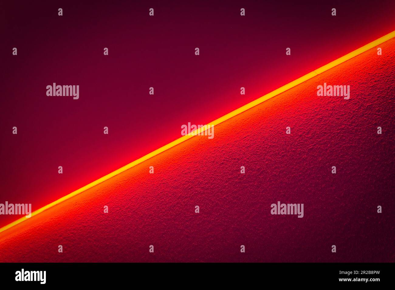 Una vivace luce al neon rossa emette una luce soffusa che crea un'atmosfera calda e accattivante. La sua tonalità elettrizzante aggiunge un tocco di eccitazione. Foto Stock