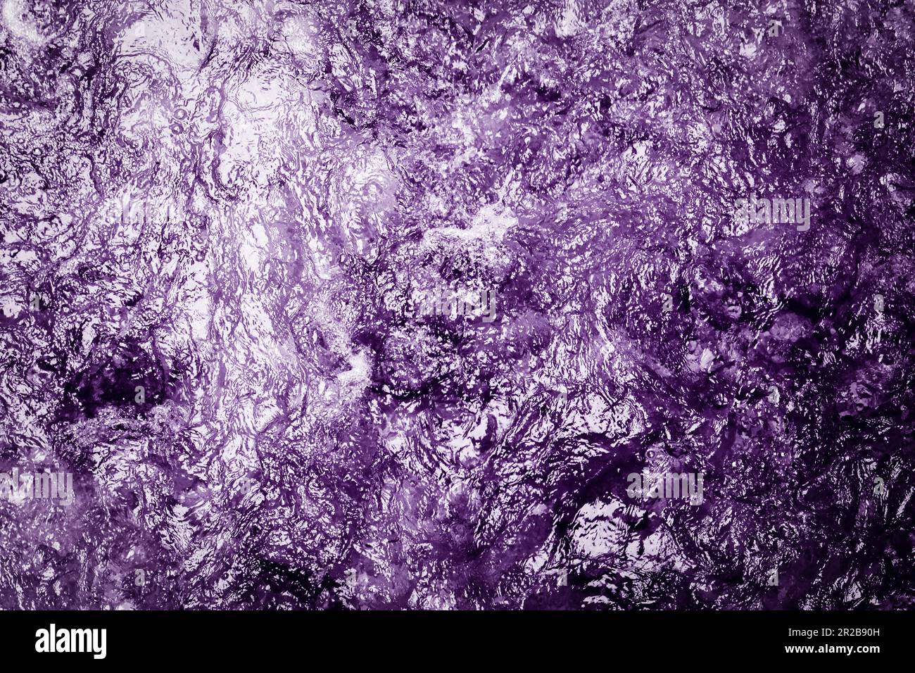 L'acqua viola astratta scorre con grazia, creando una vista ipnotizzante. La sua vivace tonalità danza con la luce, evocando un senso di mistero. Foto Stock