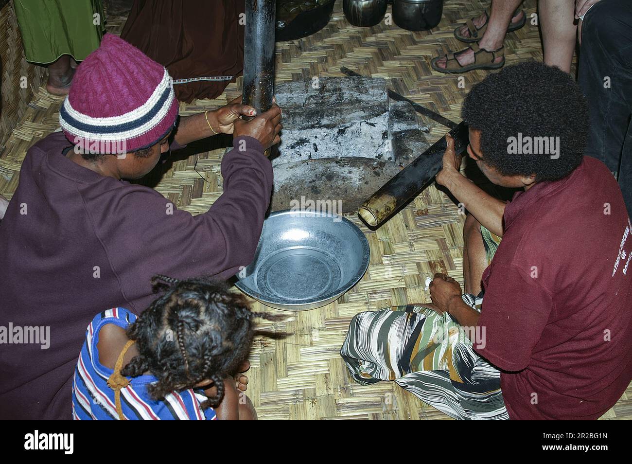 PNG, Papua Nuova Guinea; Highlands orientali; Goroka; Papuan donne preparare un pasto all'interno di una capanna; Papua-Frauen bereiten in einer Hütte eine Mahlzeit zu Foto Stock