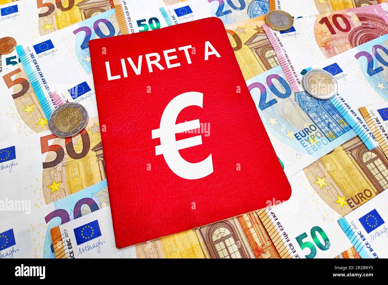 Livret In cima ad una pila di banconote e monete in euro. Il Livret A è un prodotto finanziario storico offerto dalle banche francesi. Foto Stock