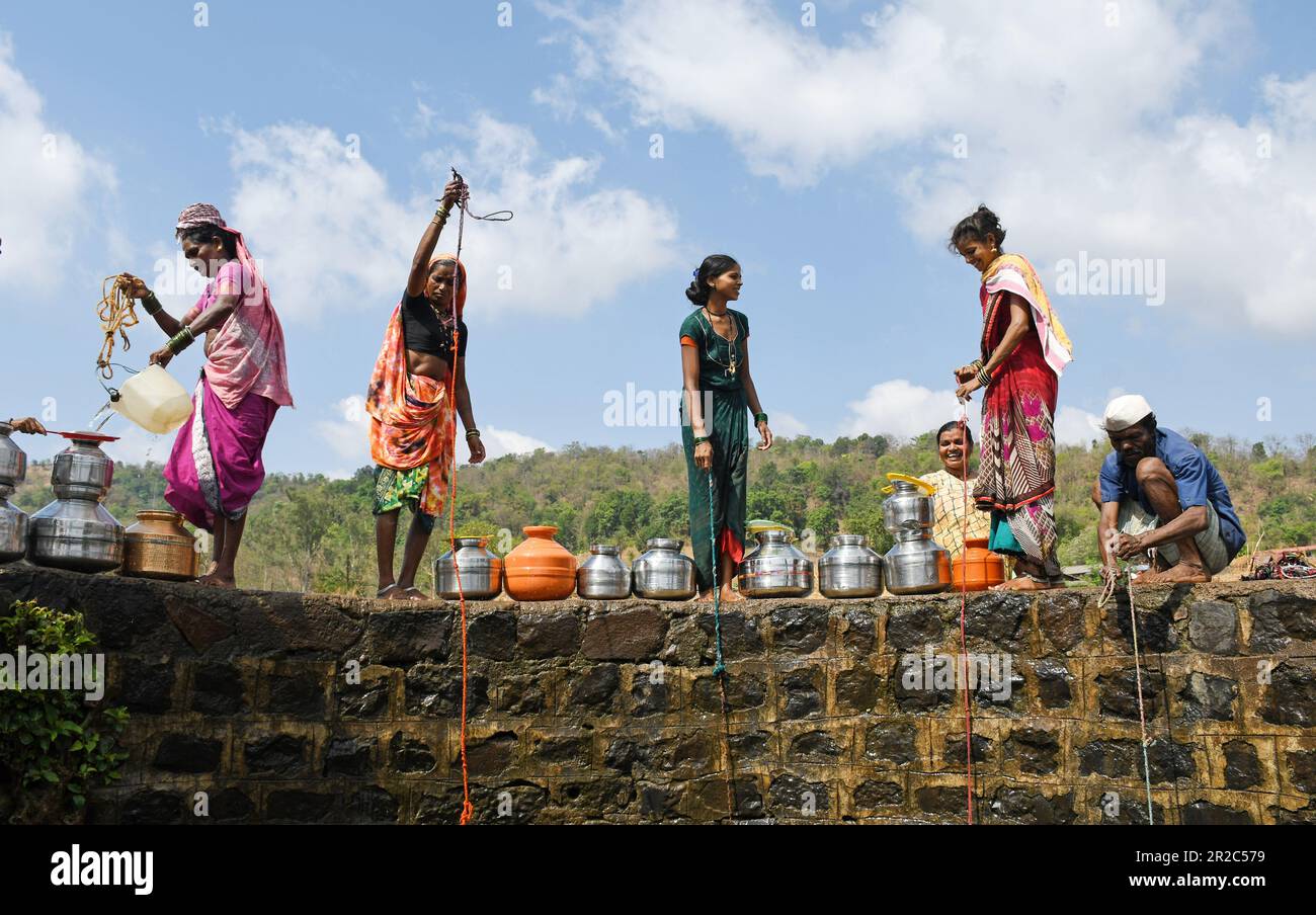 Mumbai, India. 16th maggio, 2023. Gli abitanti del villaggio in piedi sulla parete di confine attingono acqua dal pozzo nel villaggio di Telamwadi vicino Vihigaon, Shahapur taluka del distretto di Thane vicino a Mumbai. Gli abitanti del villaggio si trovano ad affrontare un'acuta scarsità d'acqua durante i mesi estivi, mentre ricevono acqua attraverso un camion che porta acqua che svuota l'acqua nel pozzo solo una volta al giorno, il che è insufficiente per loro e il loro bestiame per l'uso quotidiano. Credit: SOPA Images Limited/Alamy Live News Foto Stock