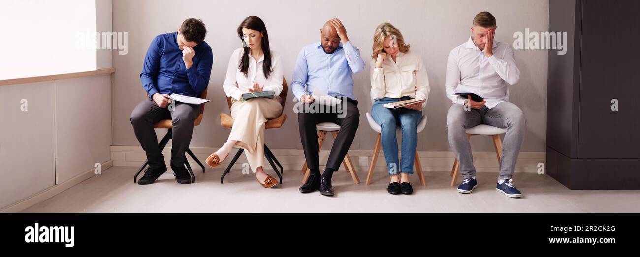 La gente di affari sono annoiarsi mentre è seduto su una sedia in attesa per il colloquio di lavoro in ufficio Foto Stock