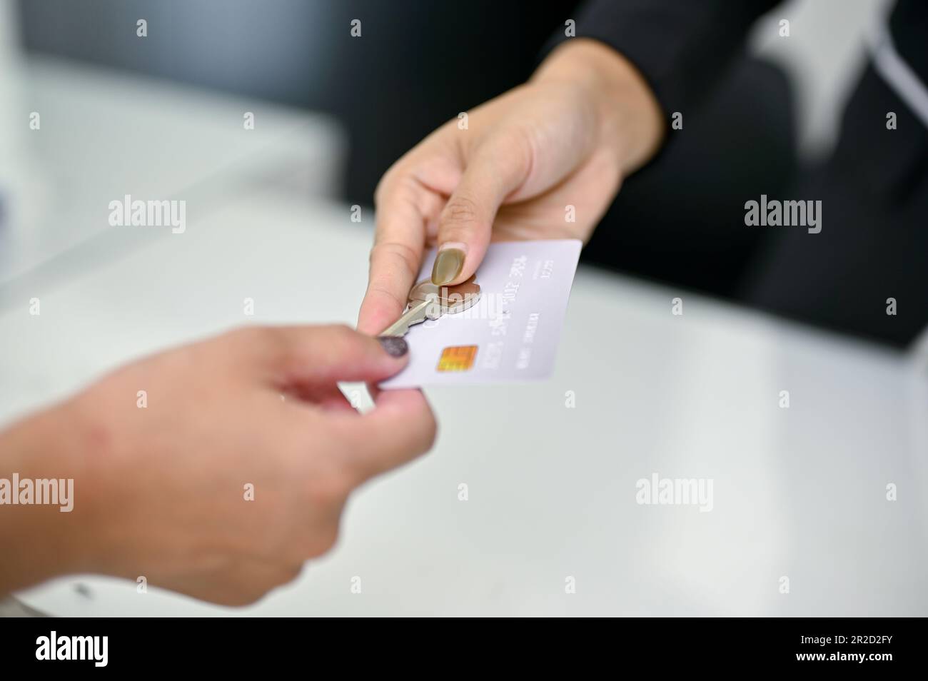 Immagine ravvicinata di un addetto alla reception che fornisce una carta di credito e una chiave della camera a un cliente alla reception. Check-in in hotel e servizi di ospitalità Foto Stock