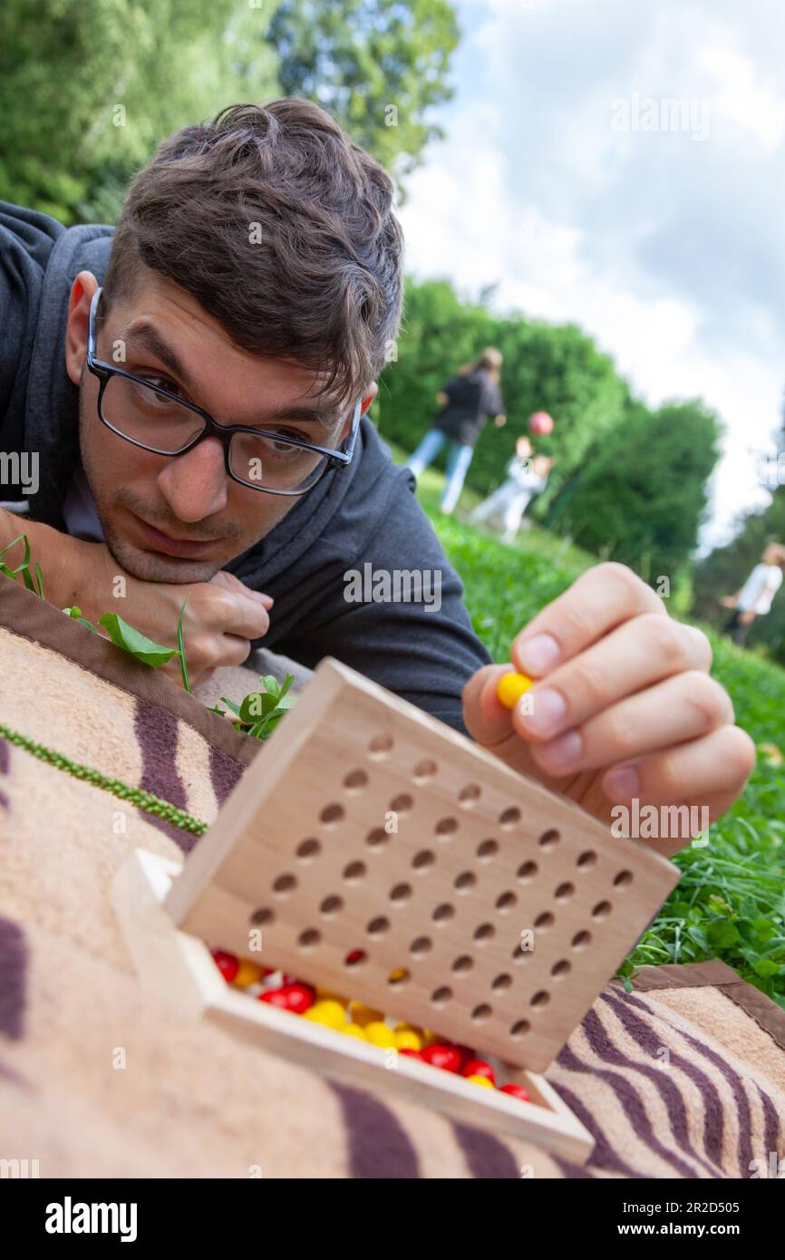 Giovane uomo concentrato che si diverta il gioco di quattro in fila che si posa su una coperta Foto Stock